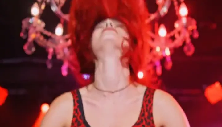 Red-haired DJ performing under a chandelier in red light