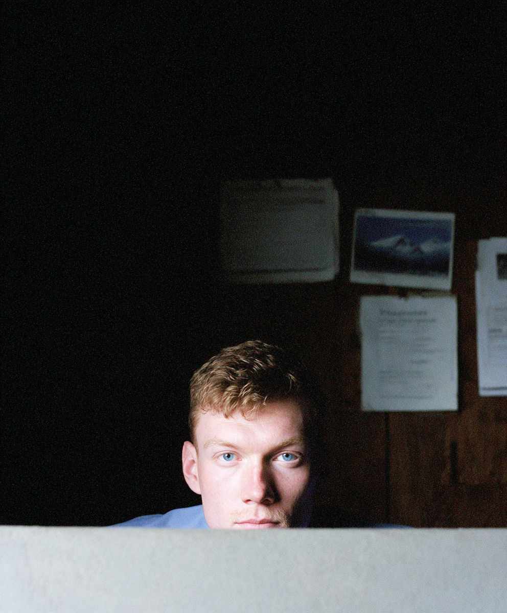 Young man peeking over a partition in a dark office