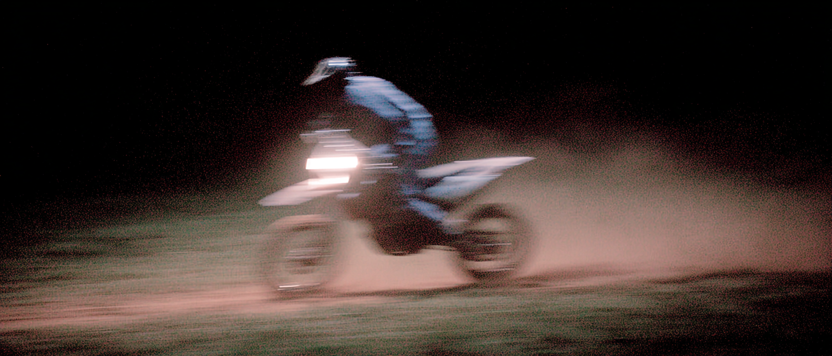 AI-generated motion-blurred motocross rider kicking up dust at night