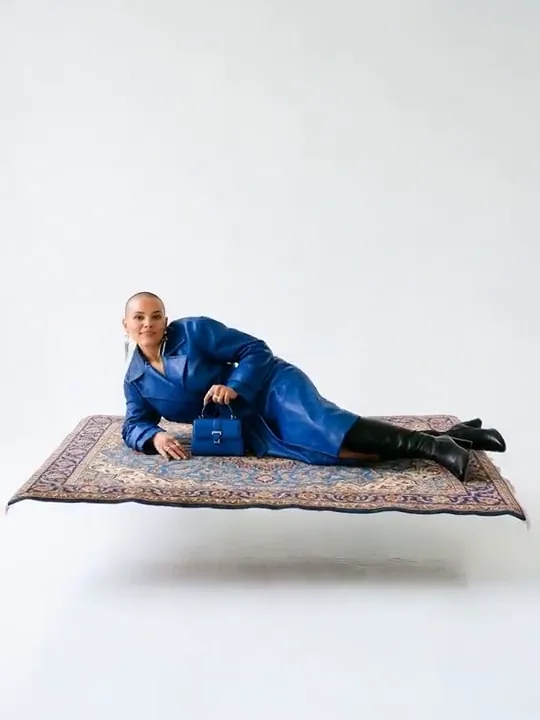 Model in a cobalt leather trench reclining on a levitating Persian carpet
