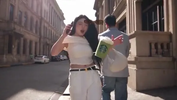 Woman holding a green iced drink on a sunlit city street