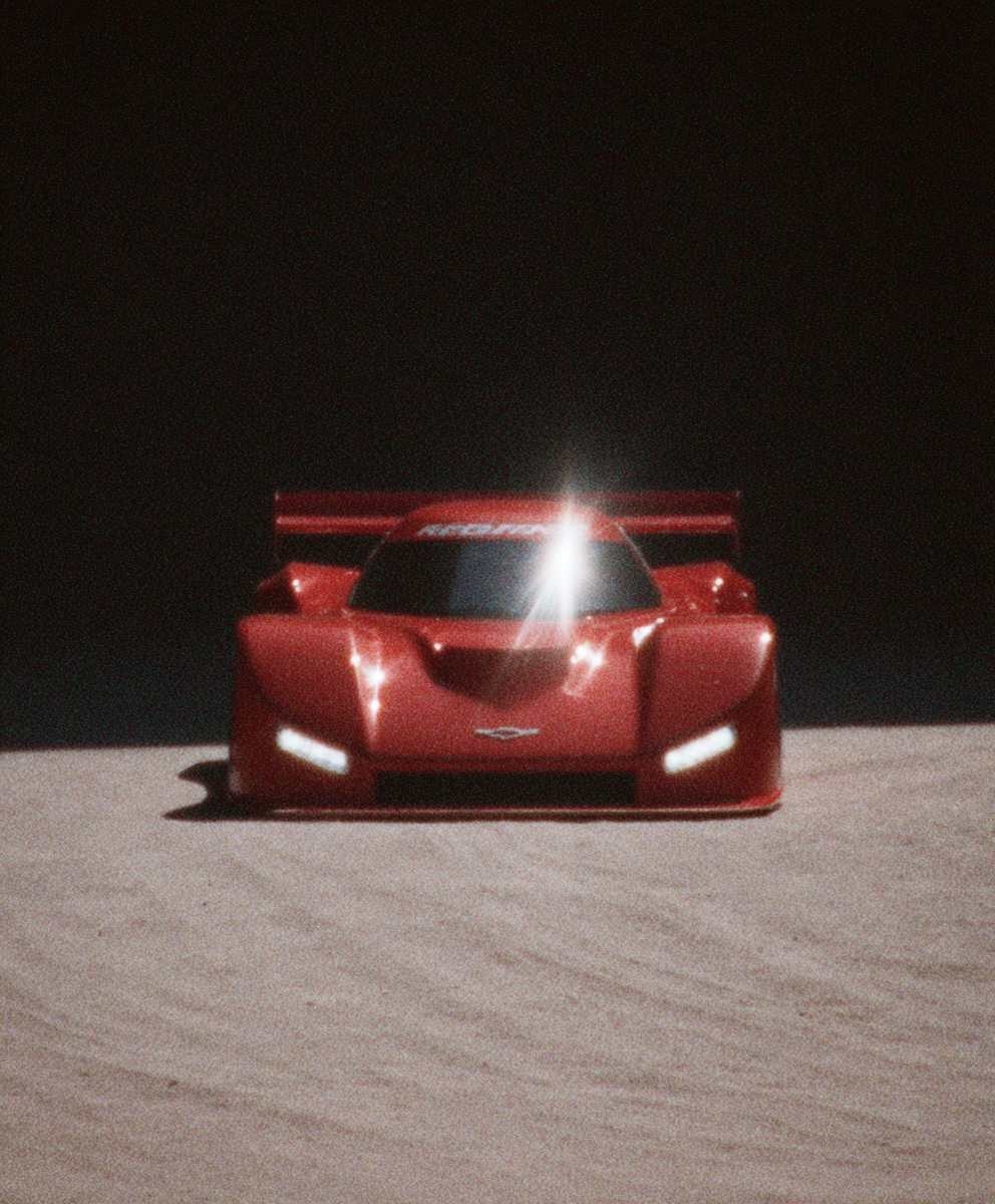 Red prototype race car under a spotlight in a dark studio