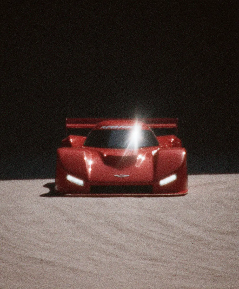 Red prototype race car under a spotlight in a dark studio