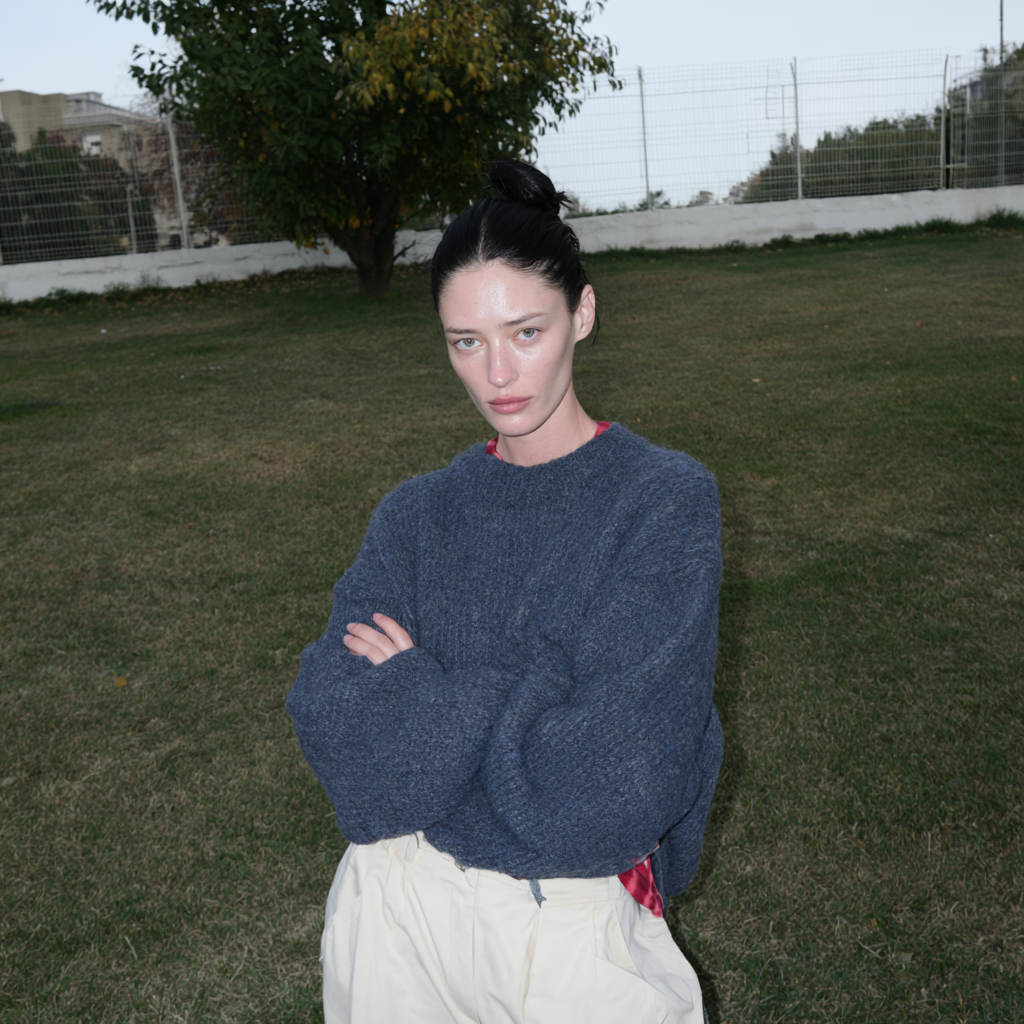 AI-generated flash portrait of a model in a blue sweater on a lawn at dusk