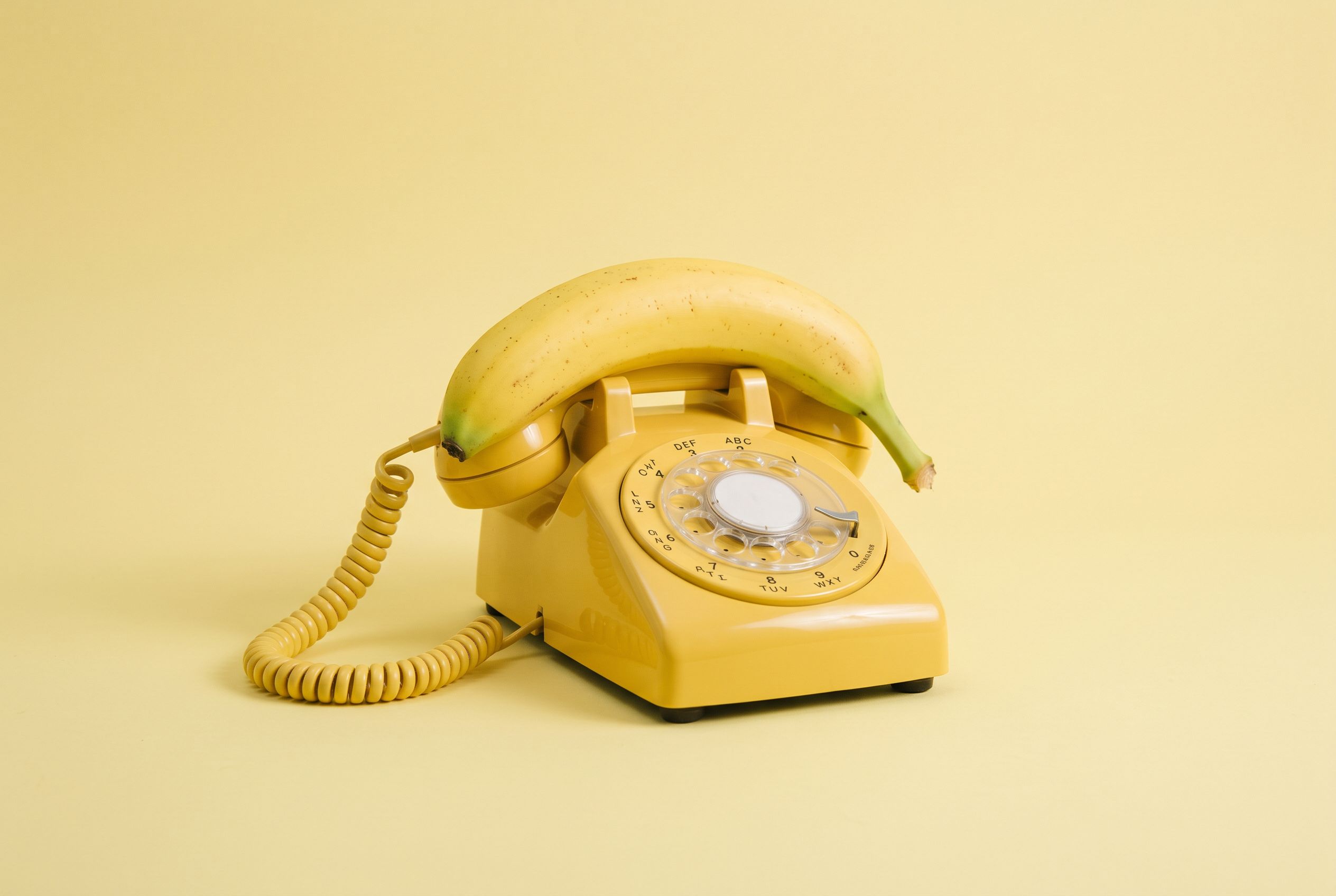 A photorealistic still life generated with Nano Banana 2.1 — a vintage yellow rotary phone with a banana as its receiver